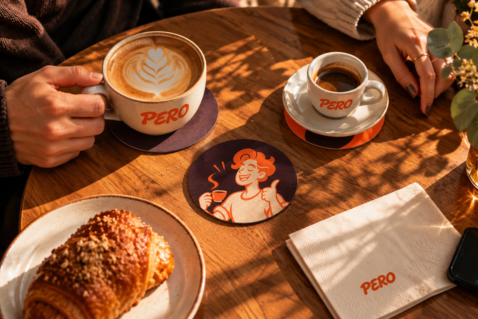 Pero coffee cups, illustrated coaster and branded napkin on a café table