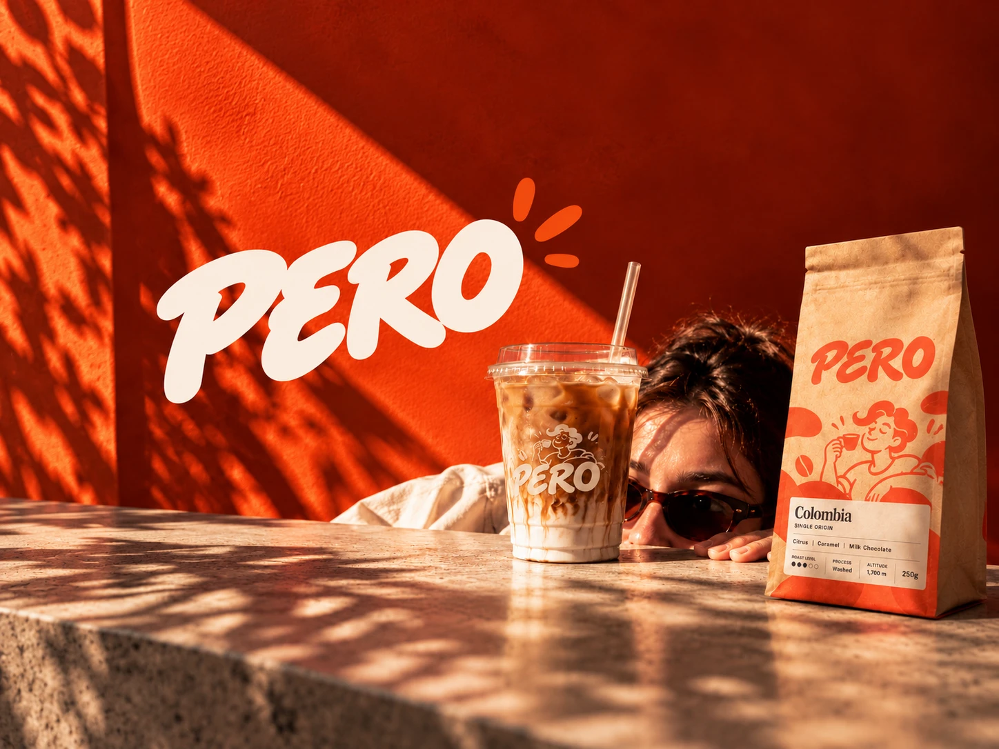 Pero iced coffee and a branded coffee packet against a sunlit orange wall